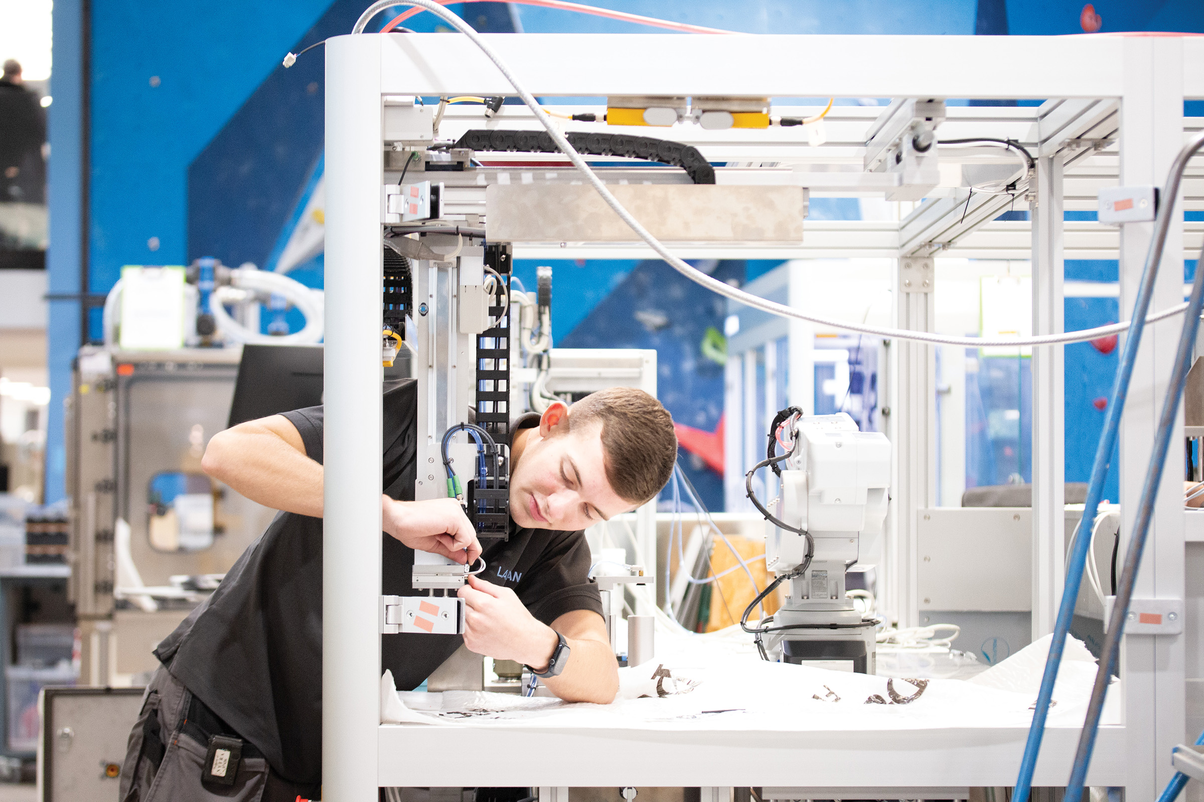 A person working on a piece of industrial equipment in a laboratory-style manufacturing environment.