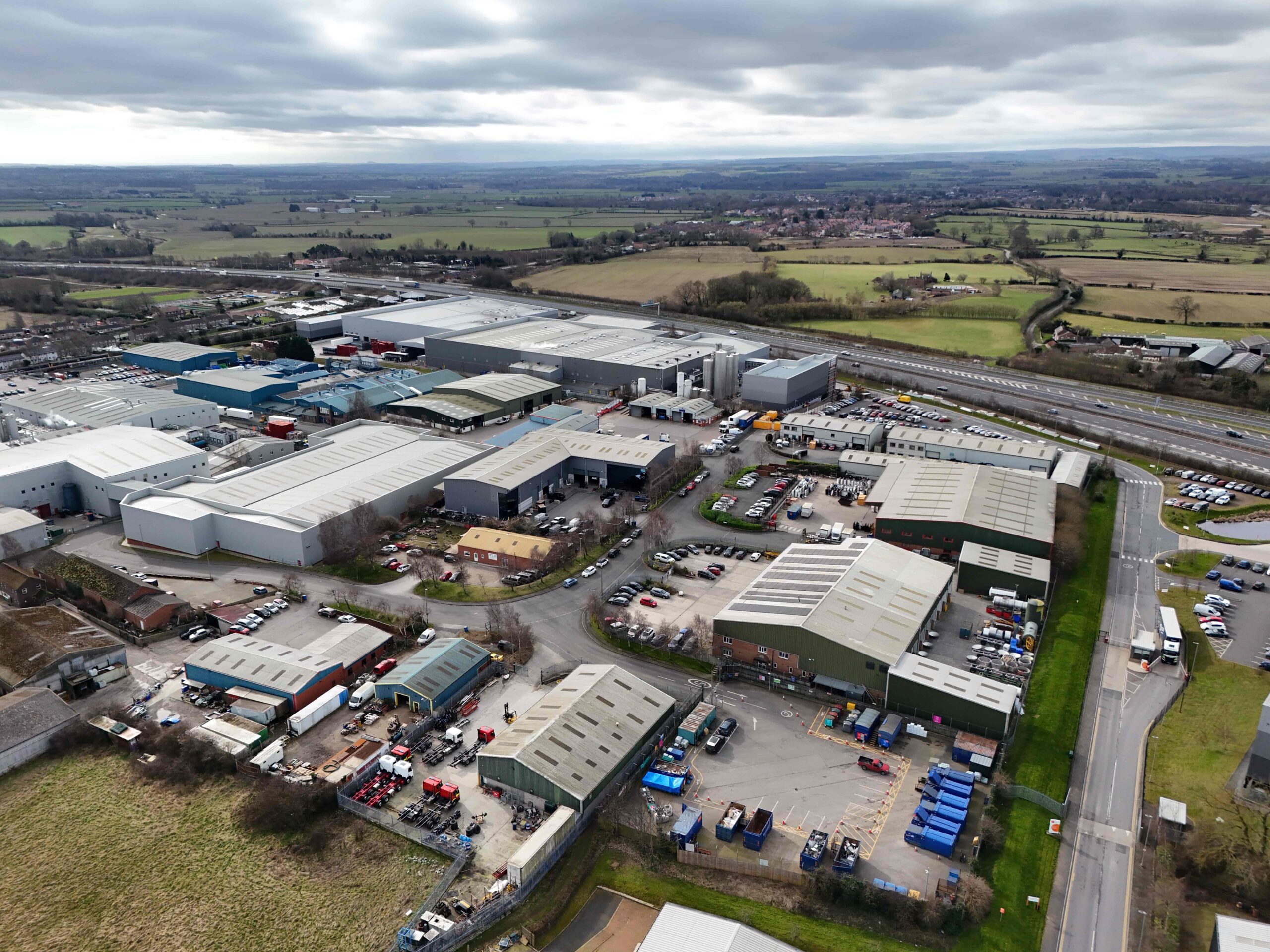 invest-strategic-Leeming Bar Ind Est_D_36 (1) Aerial photograph of the Leeming Bar Industrial Site showing industrial units and traffic movements with green fields in distance