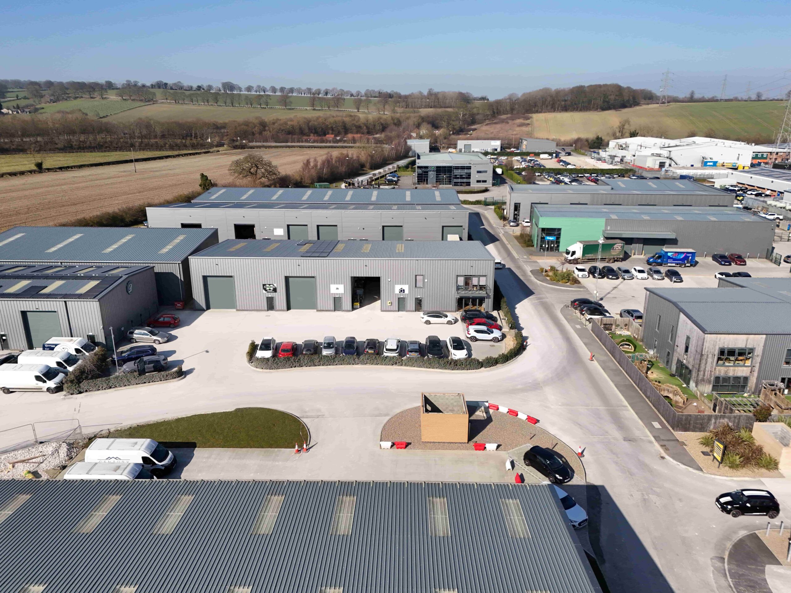 invest-strategic-Malton Enterprise Park_D_20 Photograph of industrial units with vehicles parked outside and countryside in the distance.