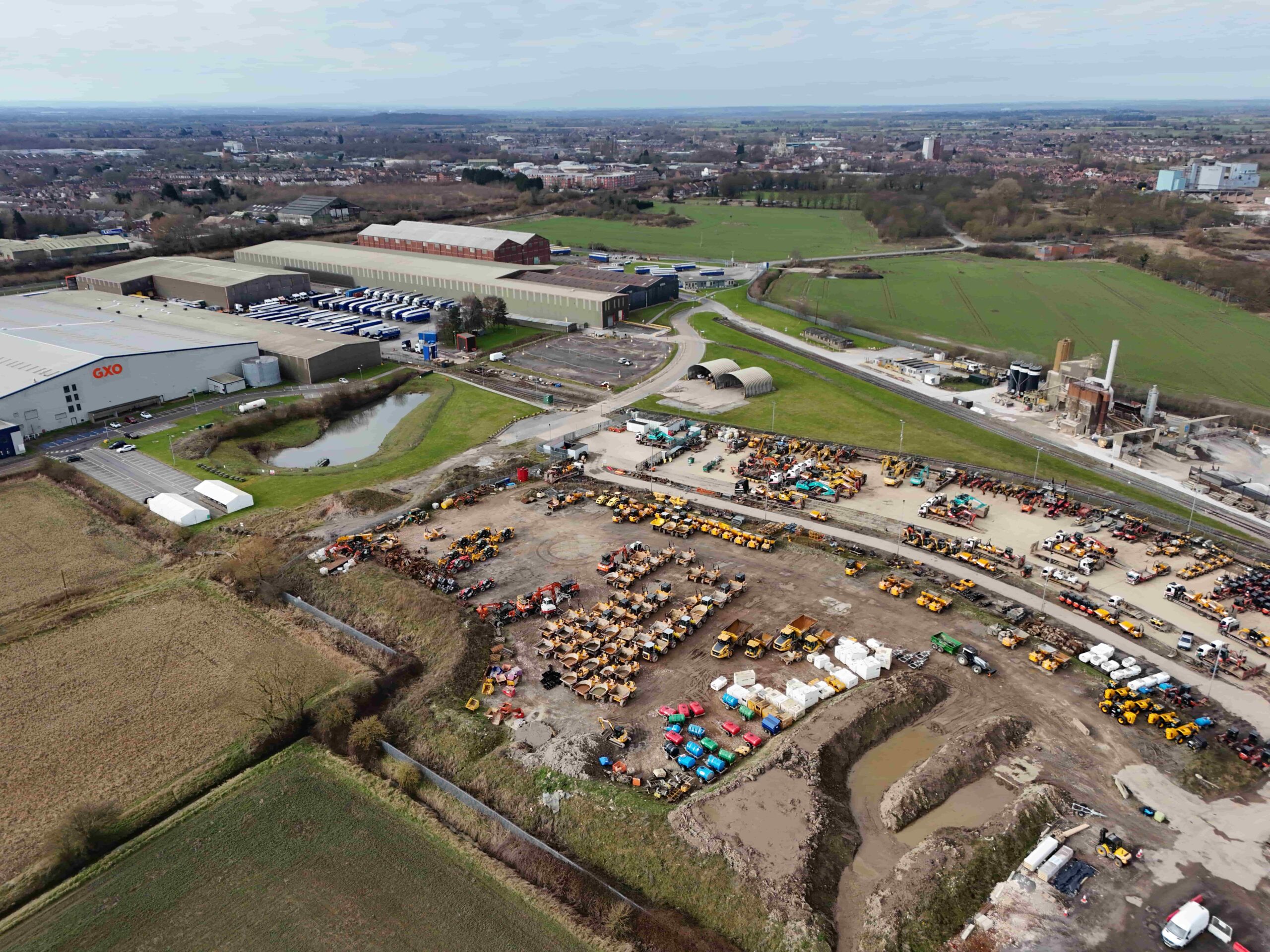 invest-strategic-Olympia Park_D_20 (1) Aerial photograph showing large industrial units in the background and open vehicle storage space in the foreground