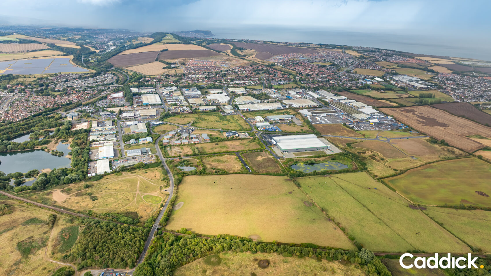 invest-strategic-caddick Aerial photograph of business units on an industrial estate with the sea in the background, taken on an overcast day.