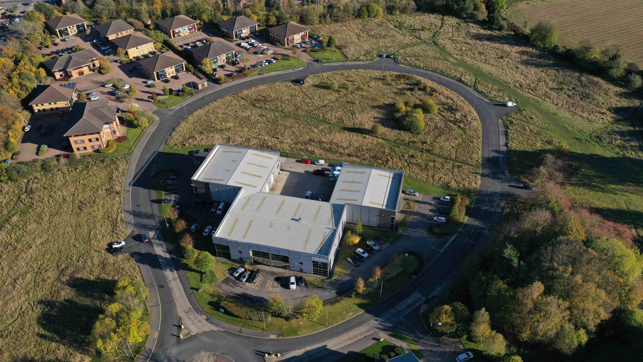 invest-strategic-colburn Aerial photograph showing a large industrial unit in a central green space with 2 and 4 story office blocks located in the northwest of the site and a business centre located in the southeast of the site.