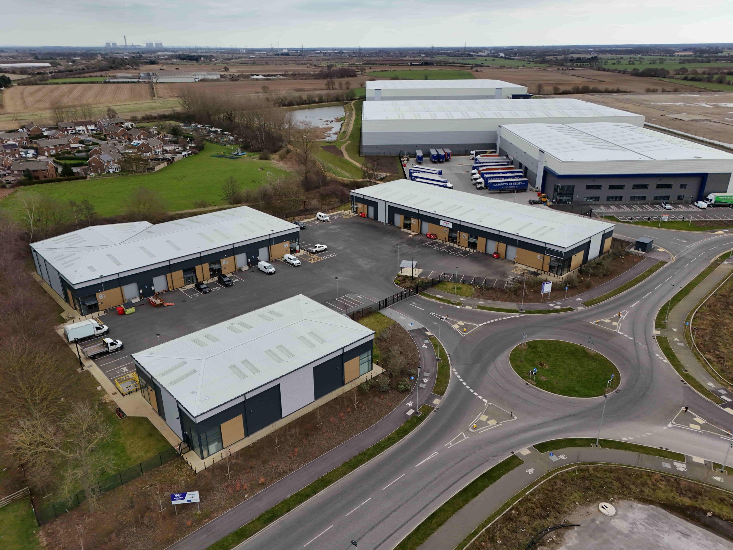 invest-strategic-konect-62 Aerial photograph of the Leeming Bar Industrial Site showing industrial units and traffic movements with green fields in distance