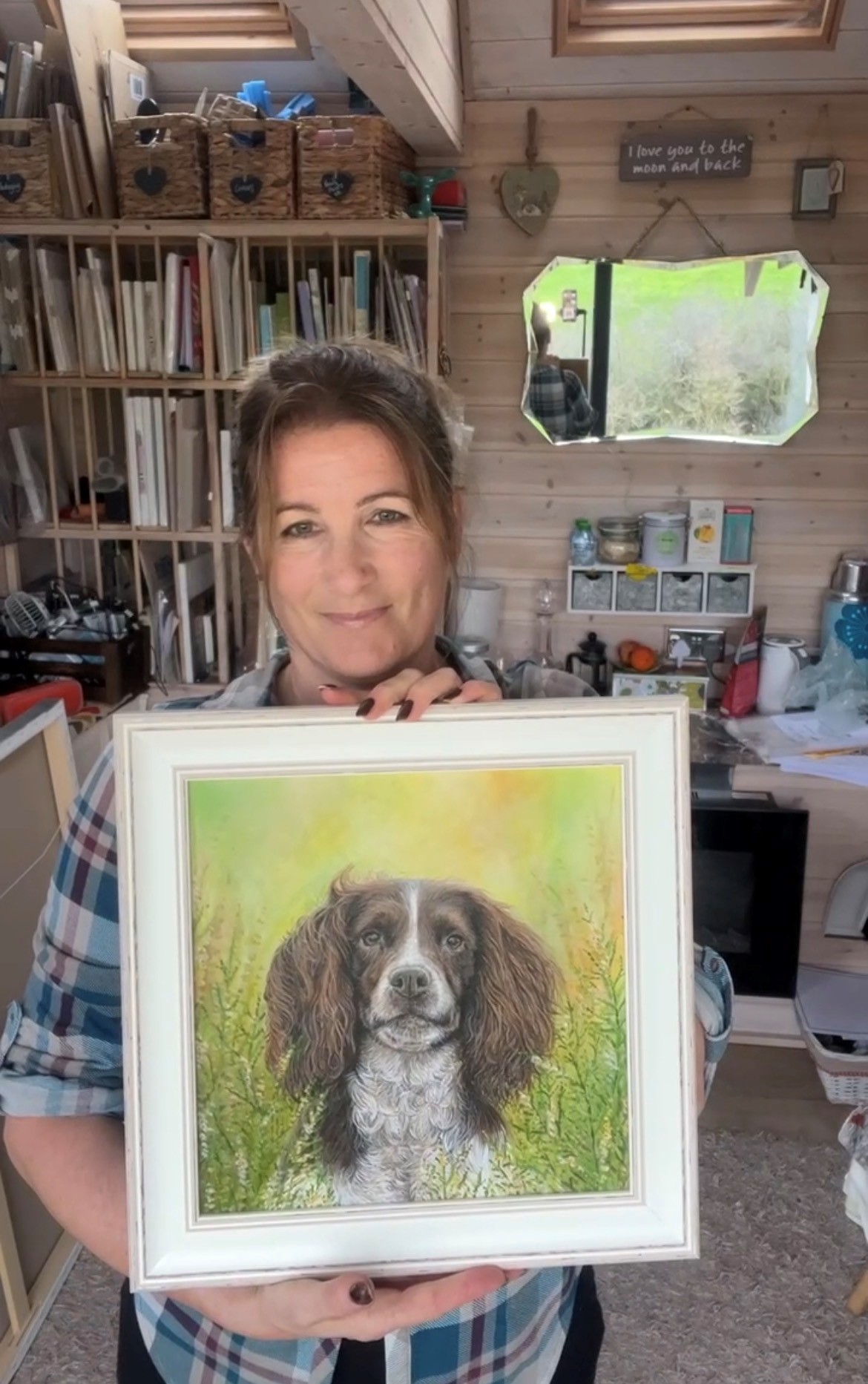 Person holding framed painting of a dog in an art studio Person holding framed painting of a dog in an art studio